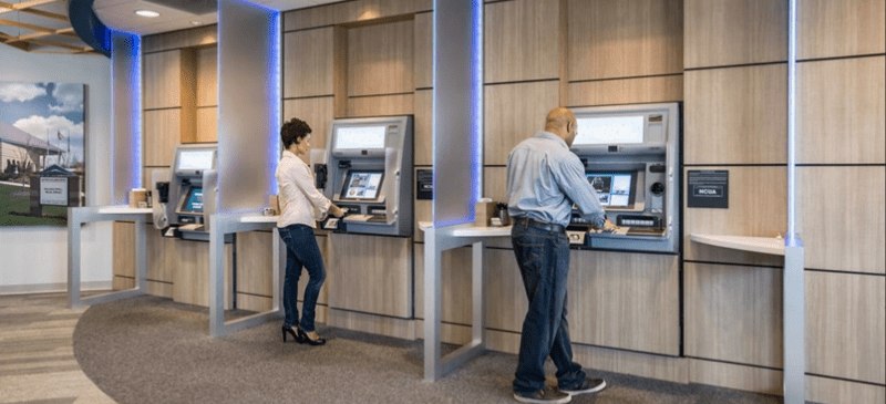 Two people at bank kiosk.